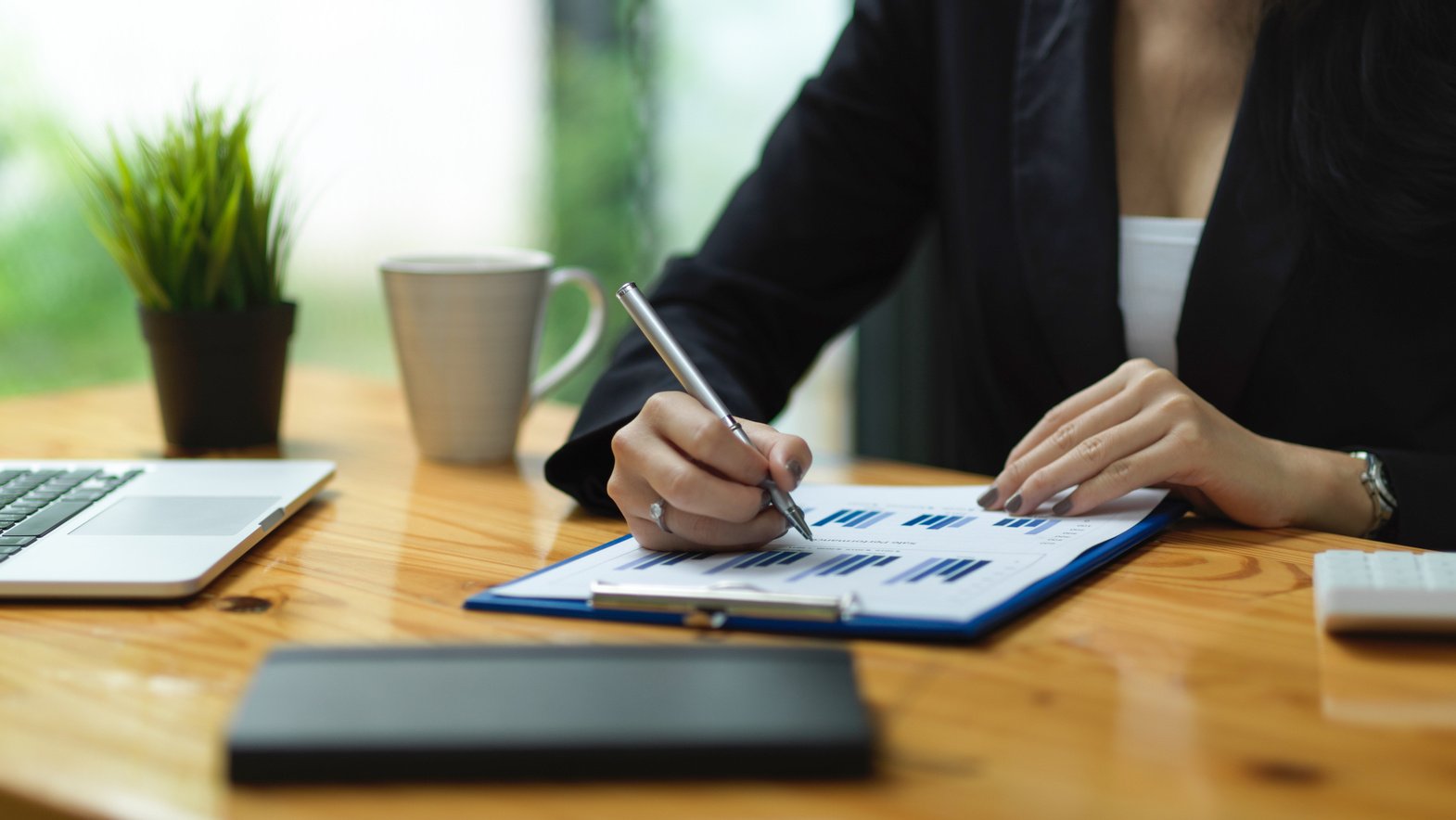 Businesswoman signing on financial proposal report at office