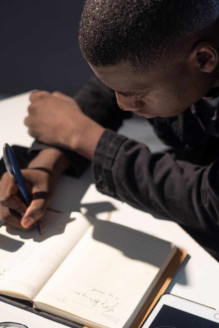 Young man intensely focused on writing in a notebook, capturing a moment of concentration.